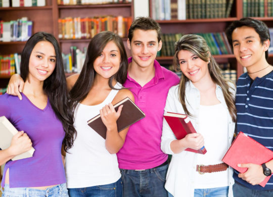 Happy group of college students smiling at the library