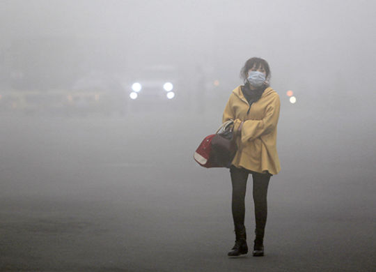 A woman wearing a face mask walks in heavy smog in Haerbin, northeast China's Heilongjiang province, on October 21, 2013. Choking clouds of pollution blanketed Haerbin, a Chinese city famed for its annual ice festival on October 21, reports said, cutting visibility to 10 metres (33 feet) and underscoring the nation's environmental challenges. CHINA OUT AFP PHOTO